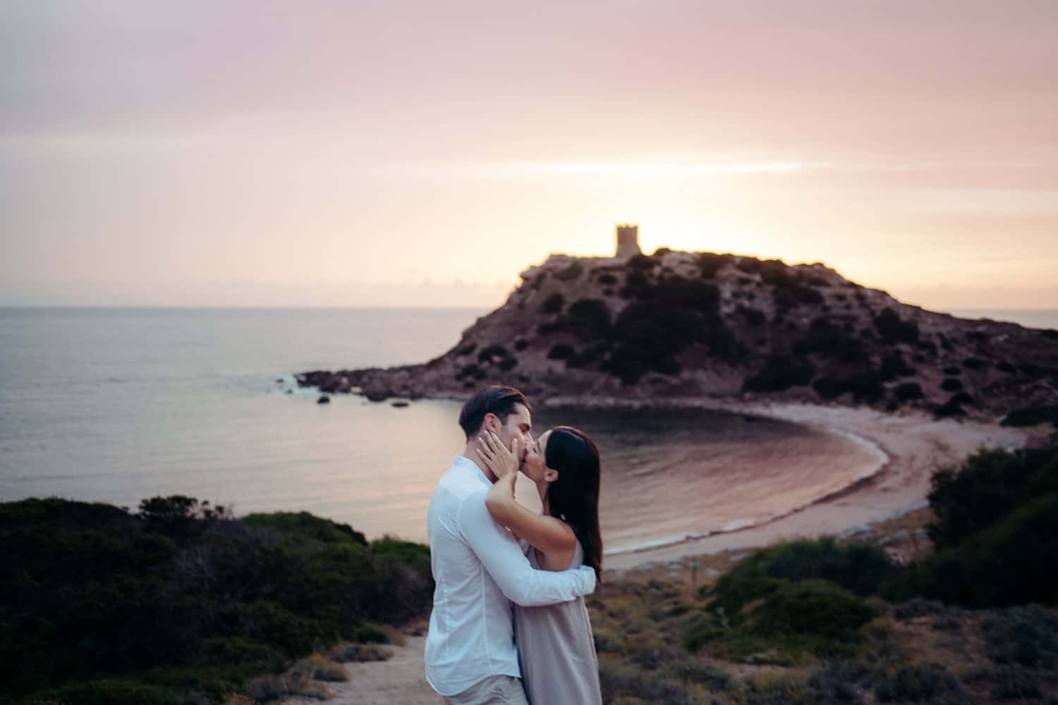 Couple walking on a cliff overlooking the sea during their engagement in Alghero.