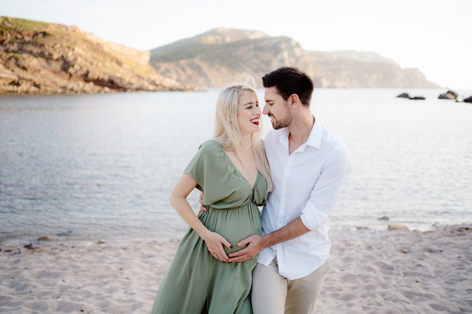 Foto di maternità ad Alghero: la futura mamma seduta su una roccia con il mare sullo sfondo