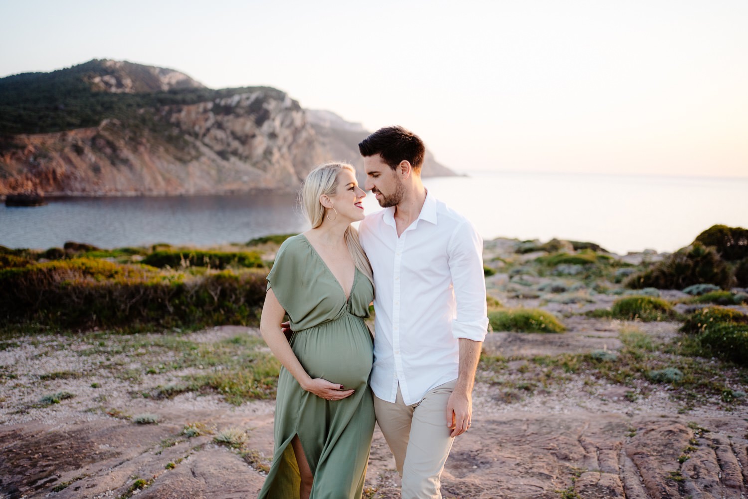 Pregnancy photo in Alghero with couple standing on the beach, holding hands